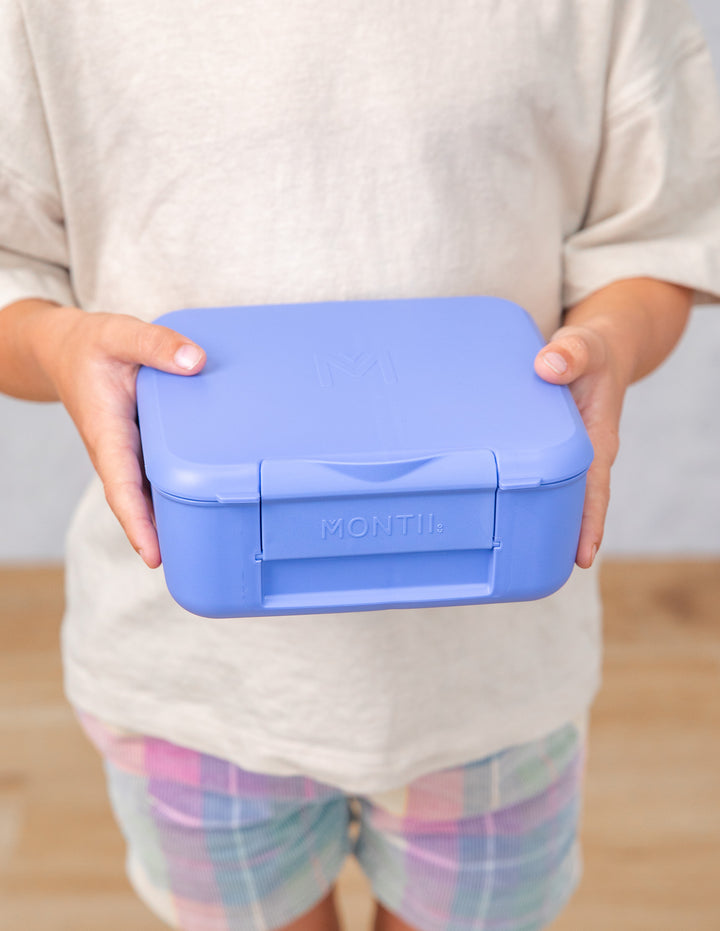 Person holding a blue lunch box with 'Montiico' branding.