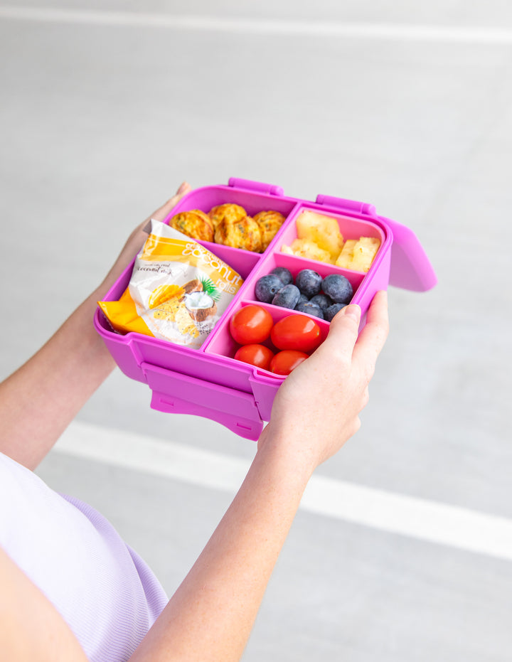 MontiiCo Bite Lunch Box - Fuchsia open lunch box with compartments and snacks