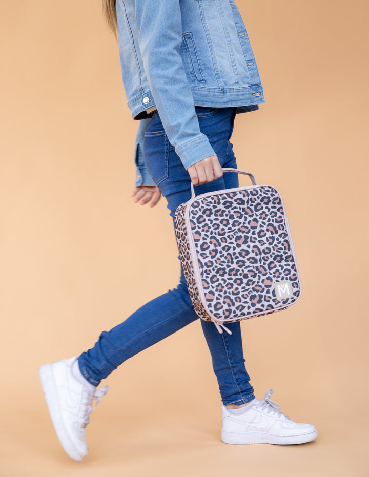 Person holding a leopard print lunch bag against a beige background