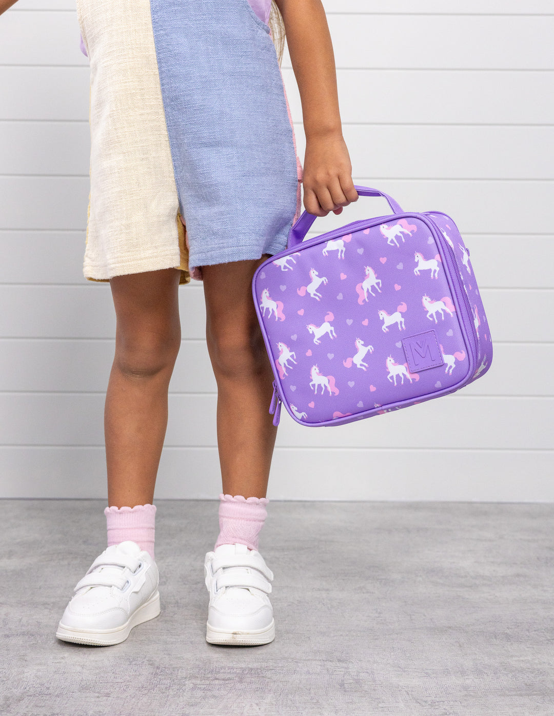 MontiiCo Medium Lunch Bag - Unicorn with child holding the bag standing