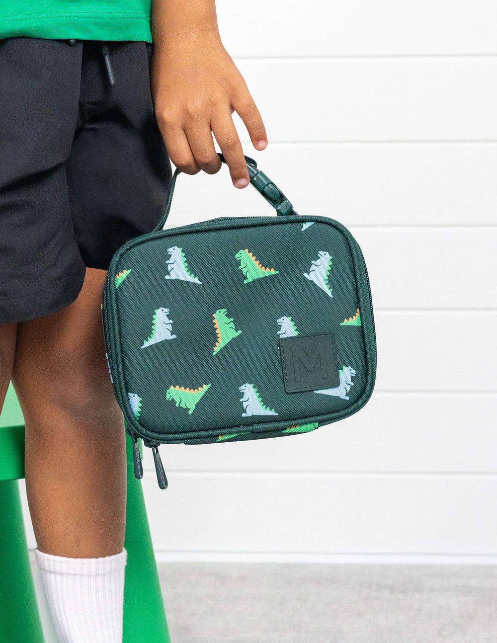 MontiiCo Mini Lunch Bag - Dinosaur child holding the bag standing