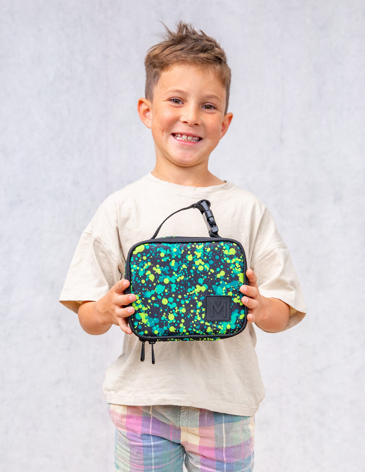 Child holding a colorful lunch bag against a plain background